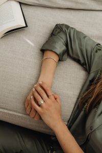 Kaboompics - Woman’s Ringed Hands on an Open Book Beside a Black Cushion