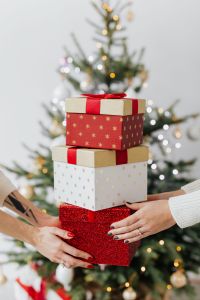 Kaboompics - Hands Holding Stacked Christmas Presents by a Tree