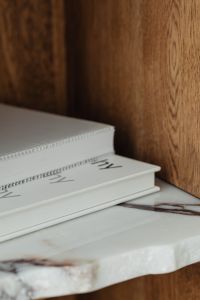 Kaboompics - White Books on a Marble Shelf Against Warm Walnut Wood