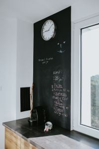 Kaboompics - Kitchen clock with a daily schedule on a blackboard