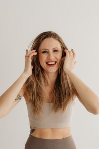 Kaboompics - Smiling Woman Touching Her Hair Against a Neutral Wall