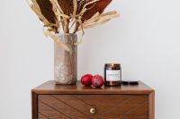 Kaboompics - Soy Candle, Red Plums and Dried Banksia on a Walnut Dresser