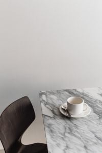 Kaboompics - White Coffee Cup and Spoon on Marble Table beside Dark Wooden Chair, Minimal Coffee Still Life