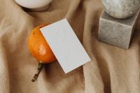 Kaboompics - Orange Fruit and Blank Business Card on Textured Linen beside a White Vase