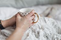 Kaboompics - Soft photo of woman on the bed with the book and cup of tea in hands