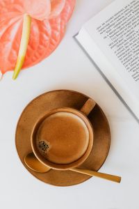 Kaboompics - Pink Anthurium and Coffee beside a Book, Portrait Flat Lay