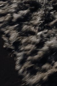 Kaboompics - Silver Whitewater Streaks Against Black Sea, High-Contrast Background