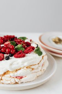 Kaboompics - Vertical Close-Up of Pavlova Cake with Red Currants and Gold-Rim Plates