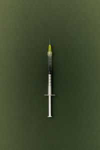 Kaboompics - Green Needle Syringe on Dark Green Background