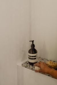 Kaboompics - Hand Reaching for Shower Essentials on a Stone Ledge