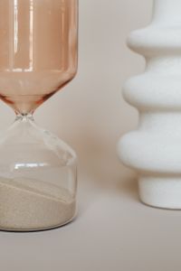 Kaboompics - Amber Glass Hourglass and White Sculptural Vase on Beige, Neutral Interior Still Life