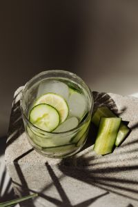 Kaboompics - High-Angle Cucumber and Lime Detox Water with Ice, Fresh Cucumber Sticks on Stone and Dramatic Shadow Background