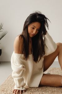 Kaboompics - Woman Tousling Her Long Hair in a Cozy Cream Sweater at Home