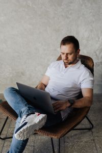 Kaboompics - The man is sitting in a chair and working with a laptop