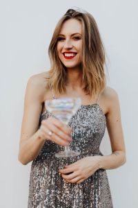 Kaboompics - Smiling Woman in Silver Dress with Champagne Flute in Foreground