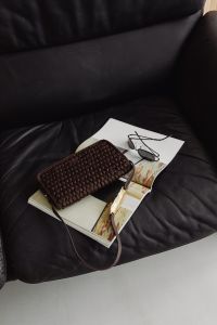 Kaboompics - Woven Handbag, Sunglasses and Magazines on a Black Leather Sofa