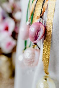 Kaboompics - Single Pink Easter Egg Ornament Hanging from Gold and Green Ribbons against Blossoms