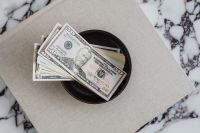 Kaboompics - Fifty Dollar Bills in a Black Bowl on Beige Linen and Marble