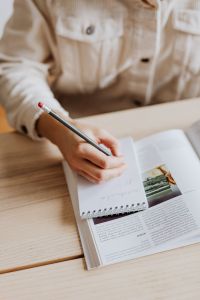 Kaboompics - Woman Writing in Notebook Over Open Book