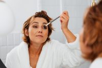 Kaboompics - Woman Applying Eye Makeup with a Brush While Looking in a Bathroom Mirror