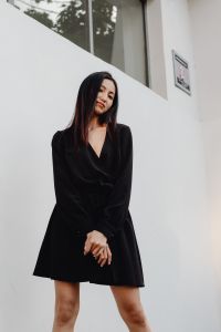Kaboompics - Asian Woman in Black Satin Dress with Crossed Arms and White Architecture