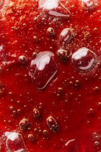 Kaboompics - Glossy Red Skincare Liquid with Large Clear Bubbles, Macro Cosmetic Texture