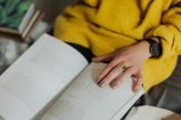 Kaboompics - Close-Up Hand on an Open Book While Relaxing in a Mustard Sweater
