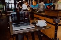 Kaboompics - Cup of coffee & MacBook laptop on table in cafe