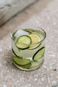 Kaboompics - Macro Close-Up of Cucumber, Lime and Ice in Detox Water on Speckled Concrete, Refreshing Summer Drink Photo