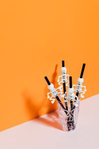 Kaboompics - Halloween Skeleton Straws in a Glass on Orange and Pink Background
