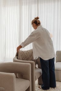 Kaboompics - Woman Arranging a Textured Throw Blanket on a Neutral Armchair
