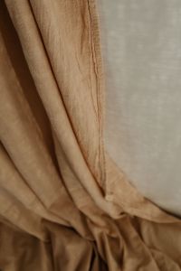 Kaboompics - Beige Curtain Hem and Gathered Folds Beside a Pale Wall, Interior Detail