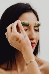 Kaboompics - Asian Woman Applying White Wildflowers Along Her Eyebrows in a Floral Makeup Beauty Portrait