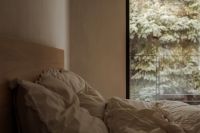 Kaboompics - White Bed with Rumpled Bedding and Evergreen View through a Window