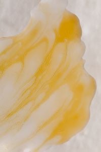Kaboompics - Golden Skincare Cream Swatch with Marbled Streaks on White Background