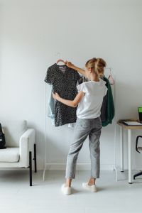 Kaboompics - Wide Bedroom Scene of Teen Girl Choosing a Black Floral Dress beside a Laptop, Wardrobe Inspiration