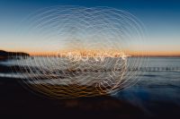 Kaboompics - Light painting. The man waving fairy lights at the sea at sunset.