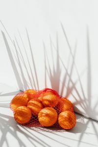 Kaboompics - Minimal White Background with Fine Plant Shadows and Citrus in a Red Net Bag