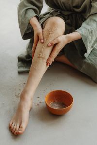 Kaboompics - Woman Exfoliating Her Leg with Sea Salt Scrub beside a Bowl