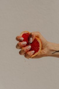 Kaboompics - Hand Holding a Grapefruit Half Against a Neutral Background with Copy Space