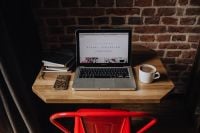 Kaboompics - Creatives desk with laptop, camera, journals and books in front of brick wall
