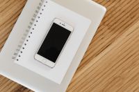 Kaboompics - White Smartphone on Open Notebook beside Laptop Edge, Neutral Wooden Desk Flat Lay