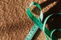 Kaboompics - Looped Green Tape Measure on Coarse Brown Knit, Sewing and Textile Background