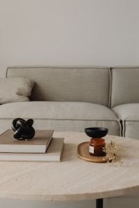 Kaboompics - Minimal Coffee Table Books, Black Sculpture and Amber Candle by a Greige Sofa