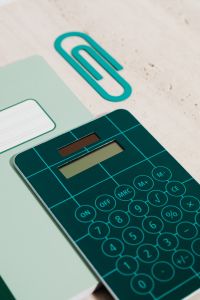 Kaboompics - Teal Calculator, Green Notebooks and Oversized Paper Clip on Limestone for Organized Study