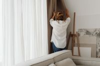 Kaboompics - Woman Adjusting Curtains in a Modern Living Room