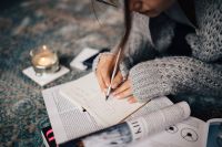 Kaboompics - Woman in a grey sweater taking notes in an organizer