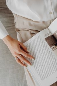 Kaboompics - Manicured Hand with Silver Ring Holding Open Architecture Book, Beige Outfit Detail