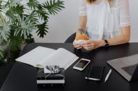Kaboompics - Female Entrepreneur Holding Sandwich Beside Laptop and Notebook