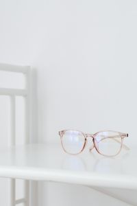 Kaboompics - Minimal Rose-Tinted Eyeglasses Low on White Table with Large Upper Copy Space